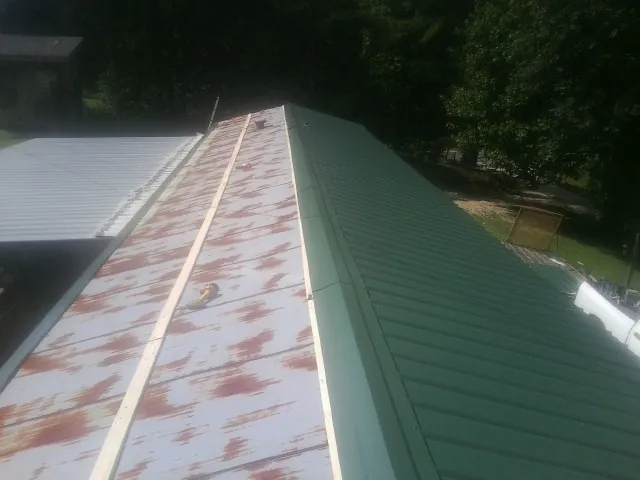 Old rusted panels beside newly installed green metal roofing — Wind Damage Roof Repair by Roofing Brothers in Dunkirk